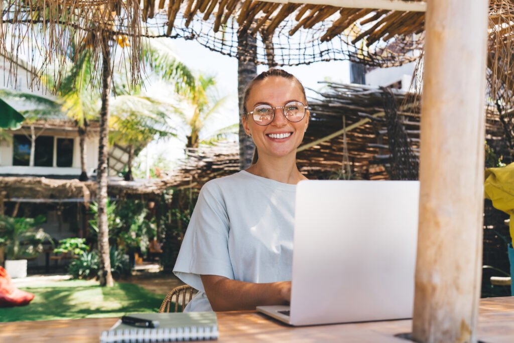 Smiling remote worker using laptop in tropical coworking space